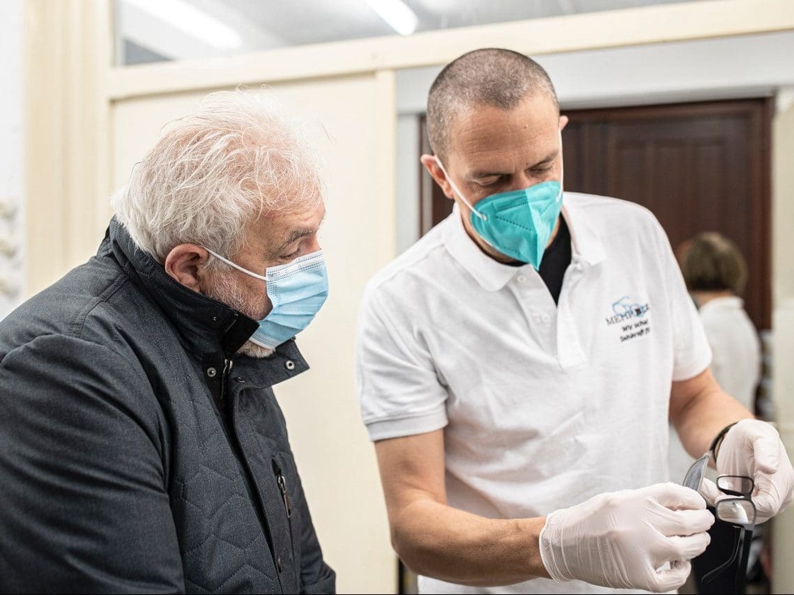 Augenoptiker zeigt Mann Brille