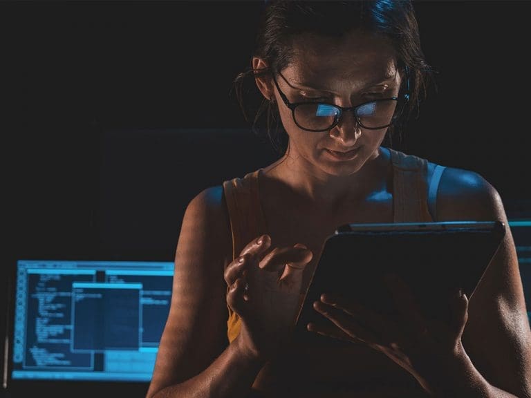 Eine junge Frau, die in einer dunklen Umgebung auf ihr Tablet schaut. Bild: Evgeniy Alyoshin / unsplash.com