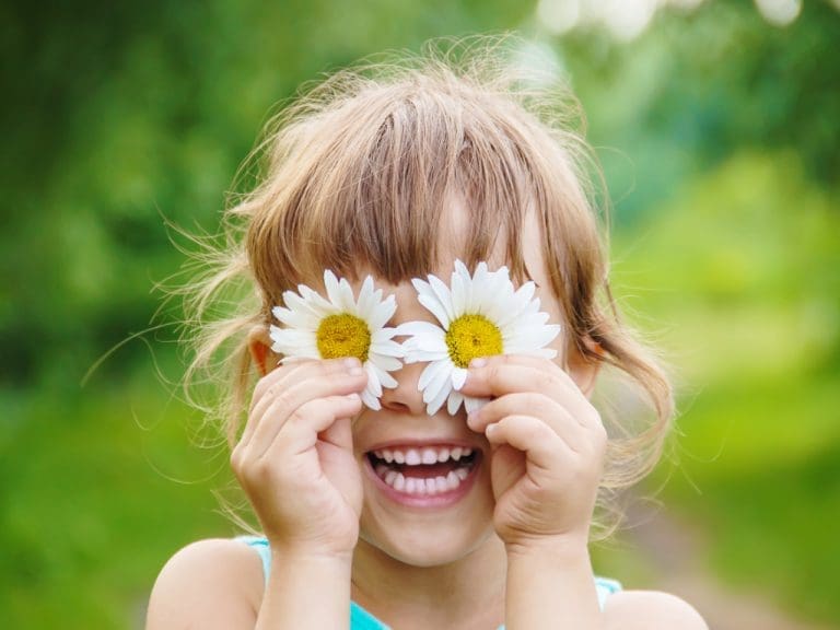 Lachendes Mädchen auf Wiese mit Sonnenblumen