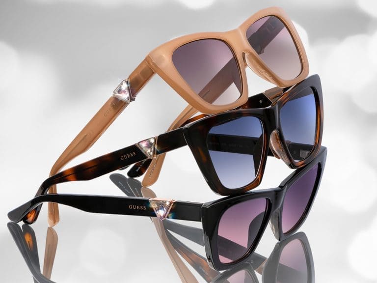 Drei Sonnenbrillen-Modelle aus der Marcolin und Guess Eyewear-Kollektion mit seitlichem Kristallstein, der das klassische Guess-Logo nachbildet.