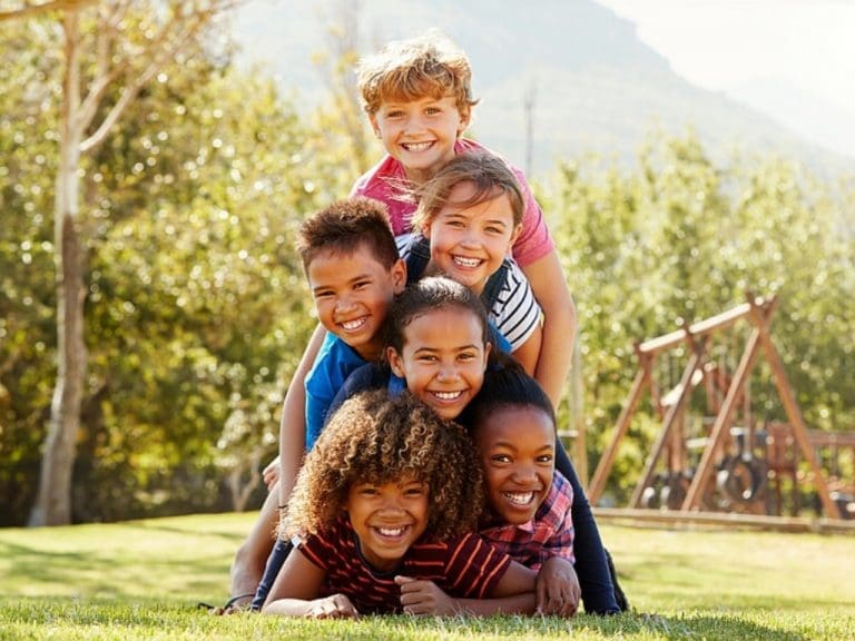 Glückliche Kinder im Freien liegen übereinander auf der Wiese