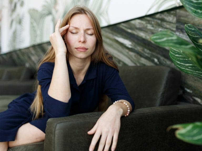 Frau hält sich Finger an die Schläfe wegen Kopfschmerzen