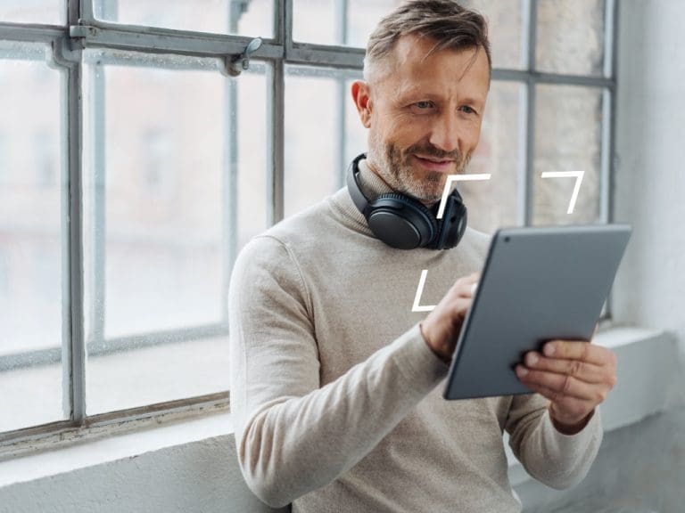 Mann im mittleren Alter schaut auf Tablet