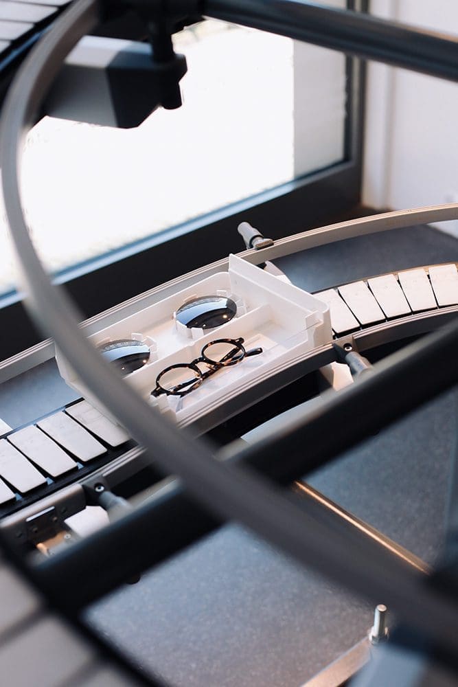 Das Bild zeigt eine Brille auf dem Weg zur Verglasung in einer vollautomatisierten Fertigungsstraße.