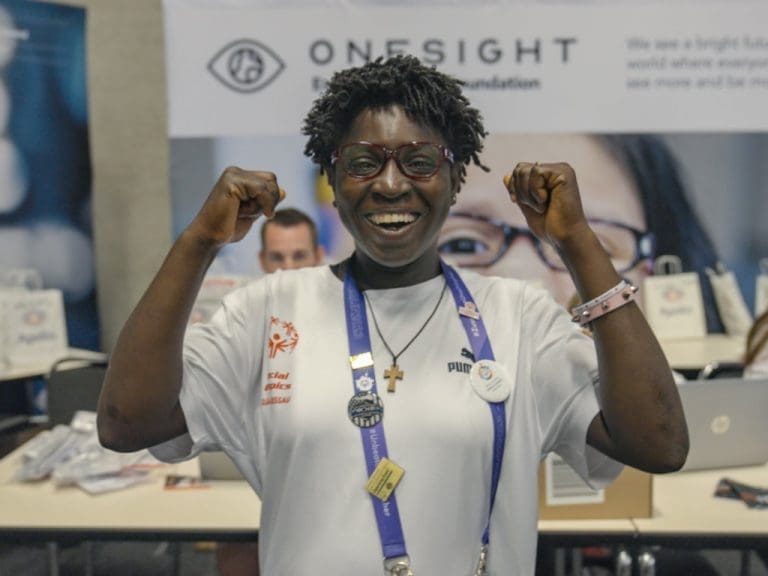 Farbige Special Olympics Athletin mit Brille streckt die Arme hoch