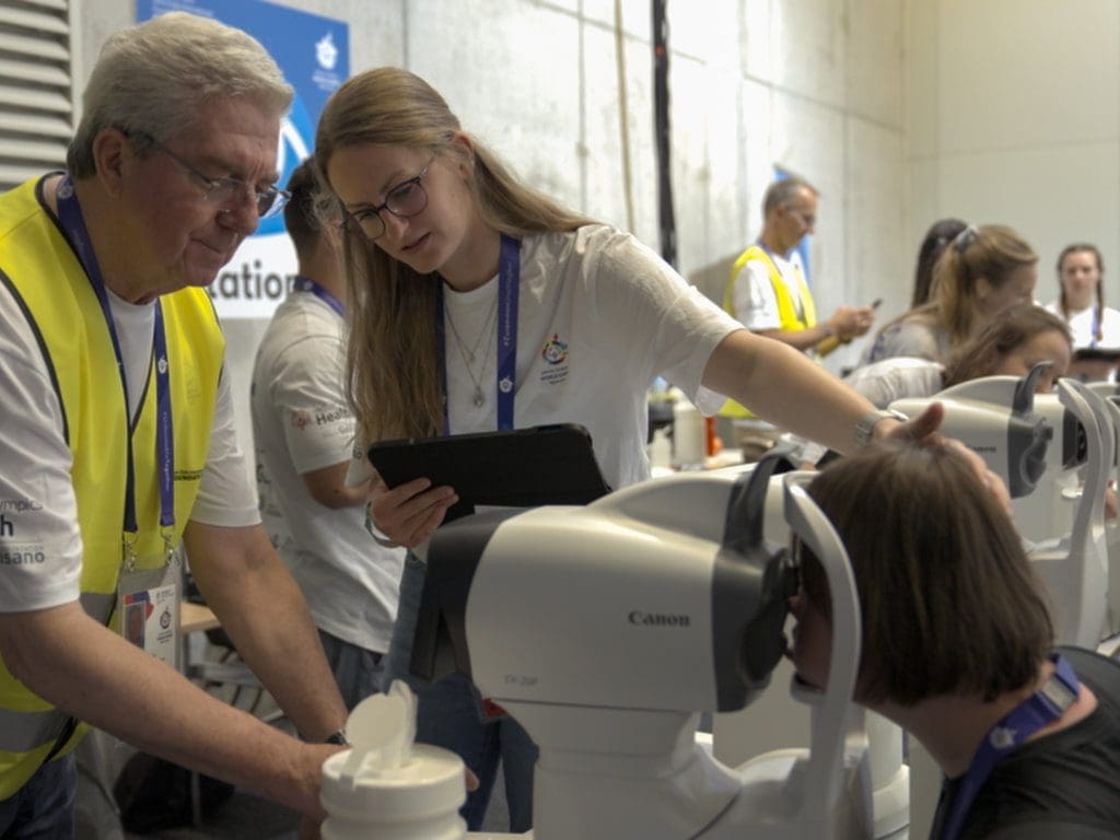 Ehrenamtliche Helfer bei Augenuntersuchung der OneSight EssilorLuxottica Foundation für Special Olympics-Athleten