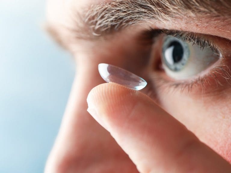 Mann setzt sich Kontaktlinse ein