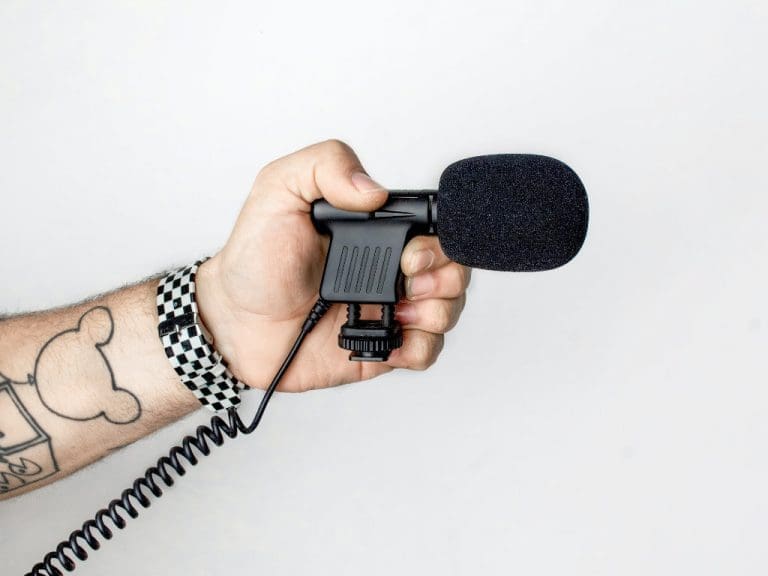 Tätowierter Arm mit Mikrophon in Hand