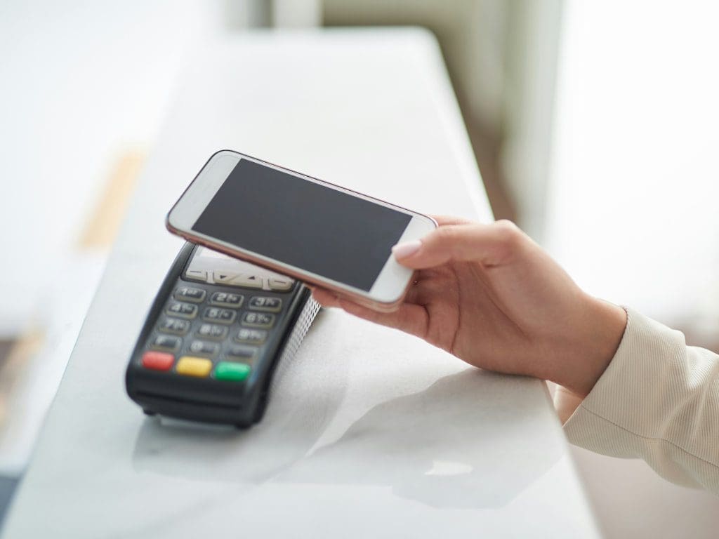 Handy wird über Bezahl-Pad gehalten für digitale Zahlung