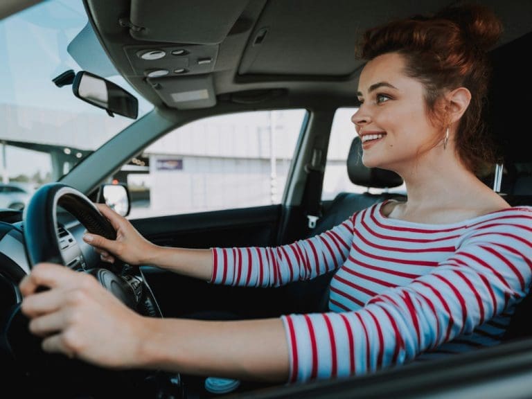 Lächelnde Frau sitzt hinterm Steuer eines Autos