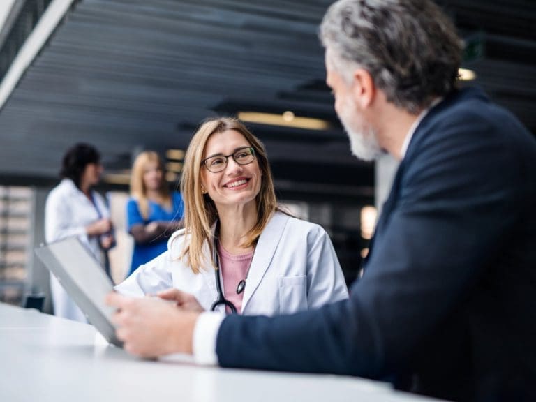 Ärztin im Gespräch mit einem Mann im Geschäftsanzug