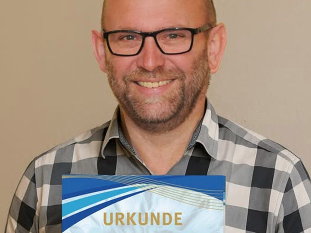 Optometrist Andreas Berkmann zeigt die WVAO Ehrenmitglied-Urkunde