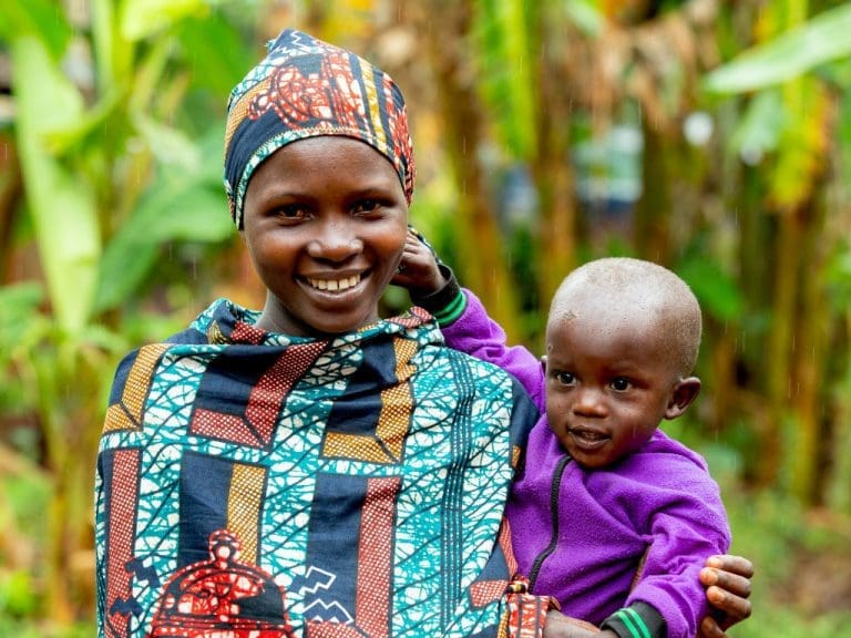 Lächelnde Mutter in Burundi hält lächelnden Säugling auf dem Arm