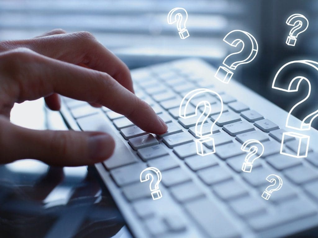 Hand tippt auf Computer-Tastatur mit, Fragezeichen sollen eine Studie symbolisieren