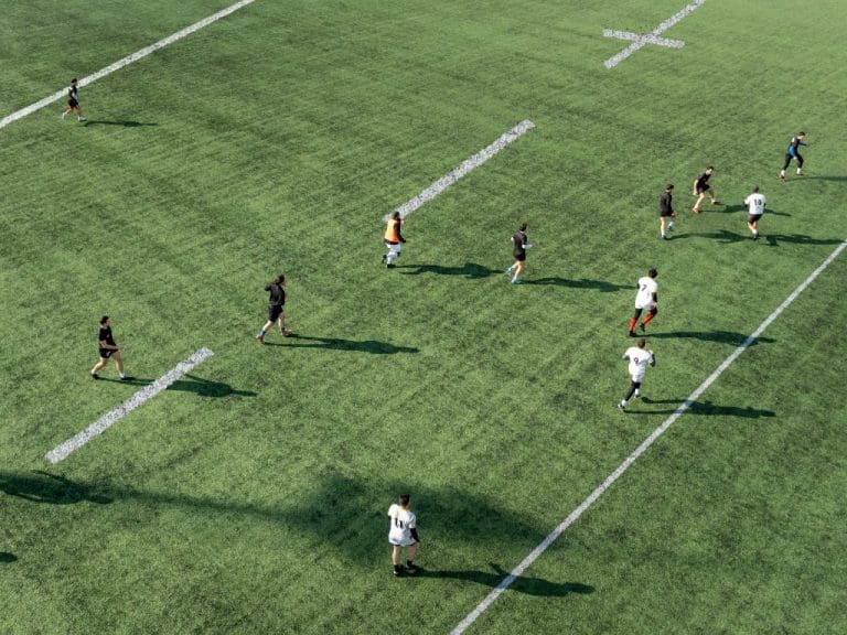 Großes Sportfeld von oben zeigt Fußball spielende Personen