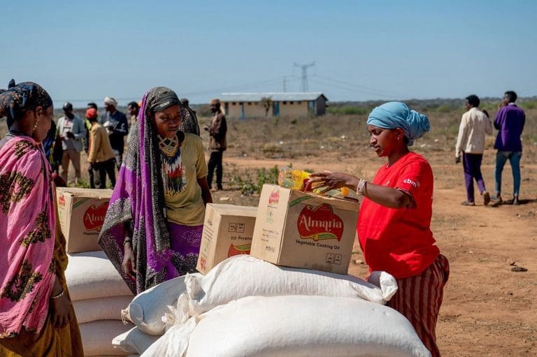 Eine Helferin verteilt Lebensmittelpakete und Speiseöl an wartende Menschen in einer Dürre-Region Äthiopiens.