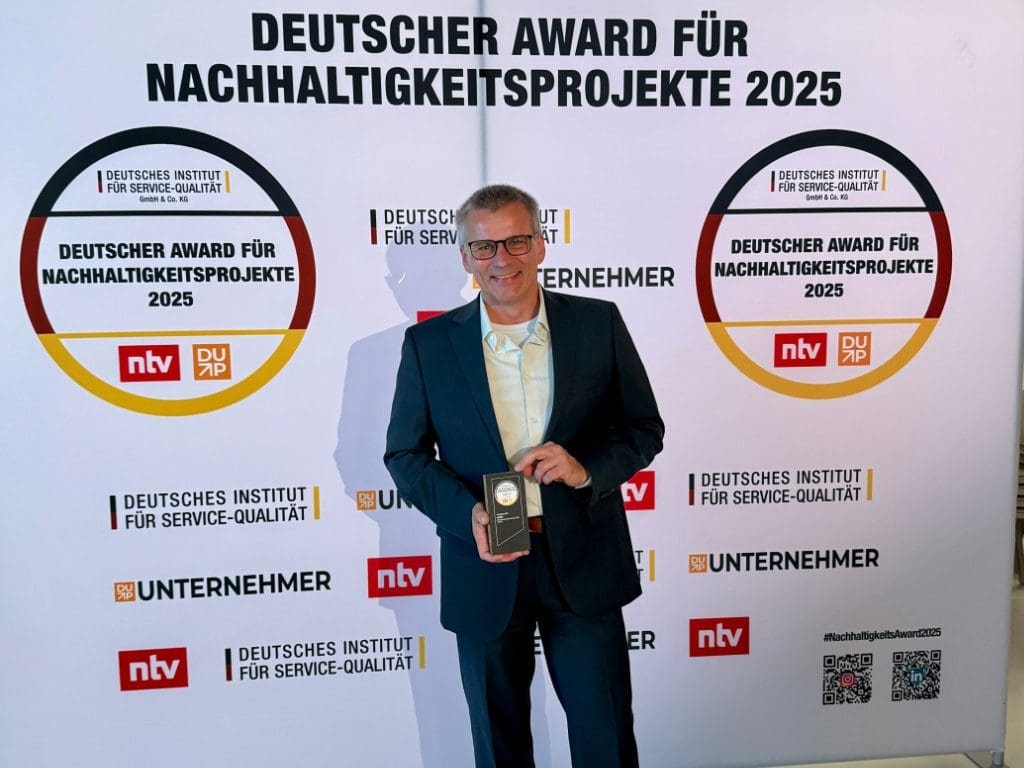 Pricon-Geschäftsführer Matthias Köste hält auf dem Big Bang KI Festival 2025 in Berlin den Deutschen Award für Nachhaltigkeitsprojekte in der Hand