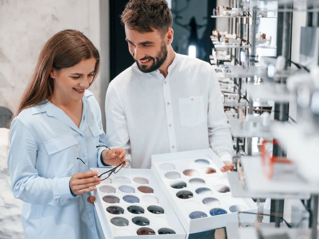 Mann und Frau schauen Brillen in einem Augenoptikfachgeschäft an