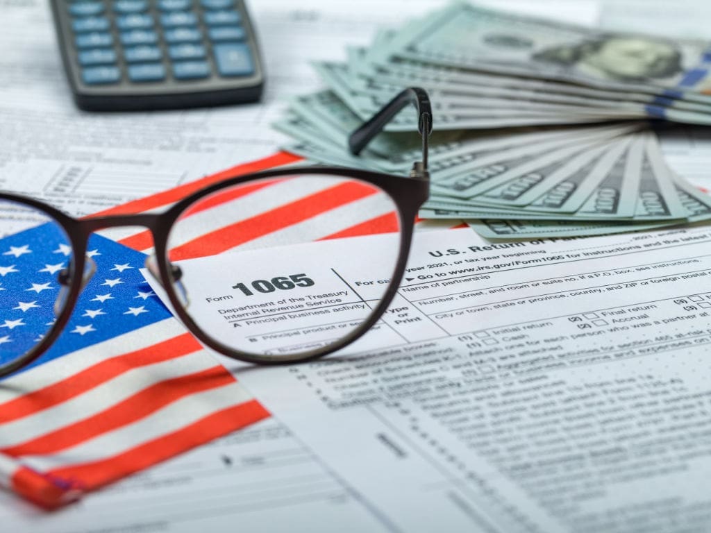 Schriftstück mit Brille, US-Flagge und Geldscheinen auf Tisch liegend