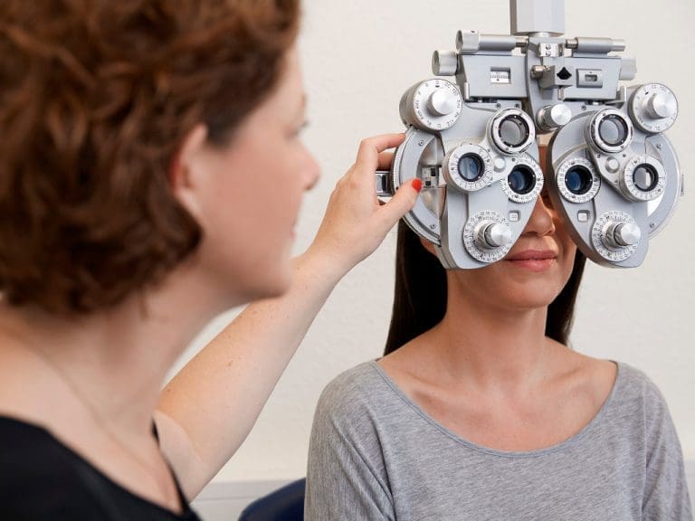 Eine Augenoptikermeisterin führt eine Refraktion bei einer Kundin durch.